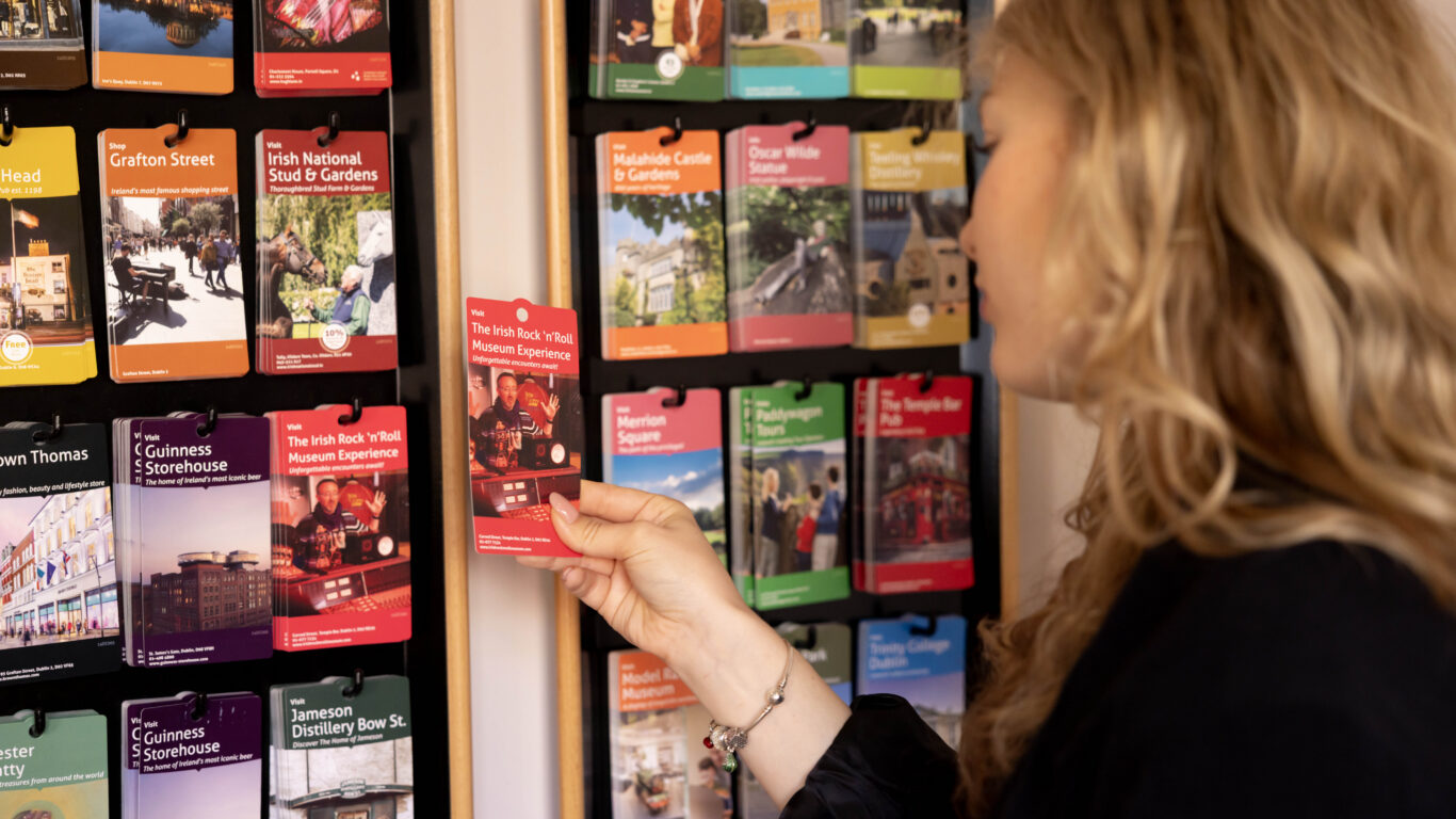 Guest selects a brochure from a vibrant display at the hotel, showcasing local attractions and tours.